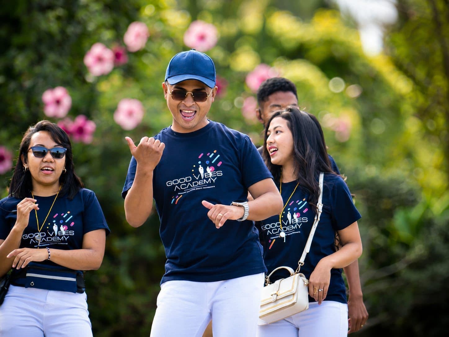 Animateur GVA souriant, casquette bleue, devant des fleurs roses