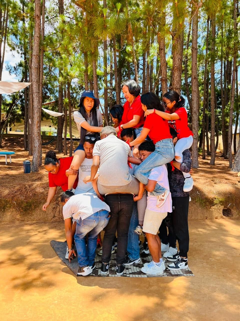 Pyramide humaine de participants en tee-shirts rouges dans une pinède